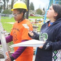 TAF Academy Builds Homeless Shelter Painting tiny home shelter in the rain.